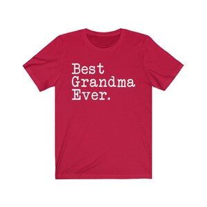 Puede incluir: Camiseta roja de manga corta con texto blanco que dice "Best Grandma Ever."