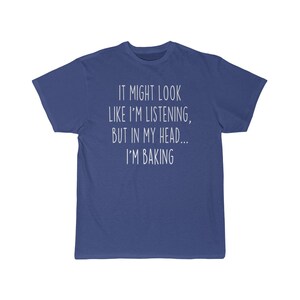 K&ouml;nnte beinhalten: Ein blaues T-Shirt mit wei&szlig;em Text, der "It might look like I'm listening, but in my head... I'm baking." lautet.