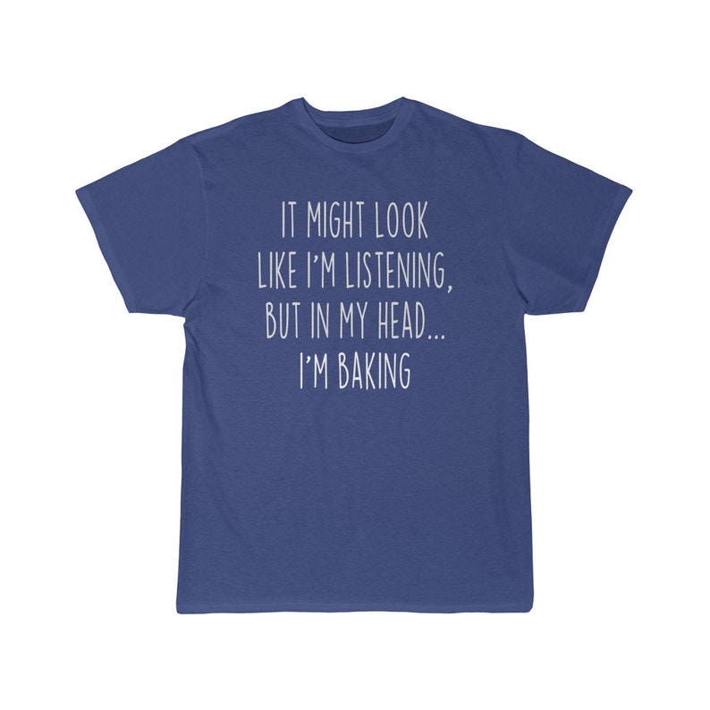 K&ouml;nnte beinhalten: Ein blaues T-Shirt mit wei&szlig;em Text, der "It might look like I'm listening, but in my head... I'm baking." lautet.