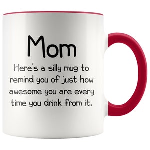 May include: White ceramic coffee mug with a red rim and handle. The mug has black text that reads "Mom Here's a silly mug to remind you of just how awesome you are every time you drink from it."