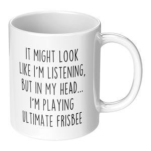 May include: White ceramic coffee mug with black text that reads: "It might look like I'm listening, but in my head... I'm playing ultimate frisbee."
