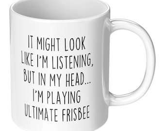 May include: White ceramic coffee mug with black text that reads: "It might look like I'm listening, but in my head... I'm playing ultimate frisbee."