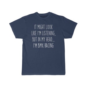 Op de afbeelding: Een marineblauw t-shirt met witte tekst die "IT MIGHT LOOK LIKE I'M LISTENING, BUT IN MY HEAD... I'M BMX RACING" zegt.
