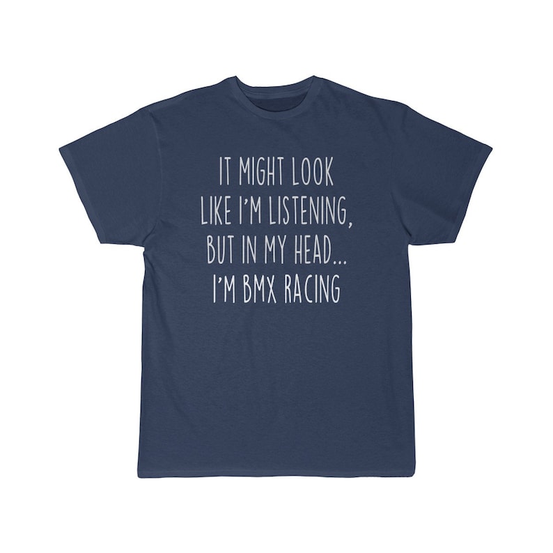 Op de afbeelding: Een marineblauw t-shirt met witte tekst die "IT MIGHT LOOK LIKE I'M LISTENING, BUT IN MY HEAD... I'M BMX RACING" zegt.