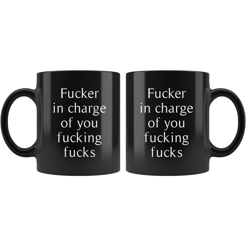 May include: Two black ceramic mugs with white text that reads "Fucker in charge of you fucking fucks". The mugs are identical and have a standard handle.