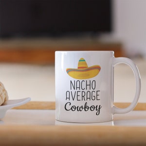 May include: White ceramic mug with a black and white graphic of a sombrero and the text "Nacho Average Cowboy".