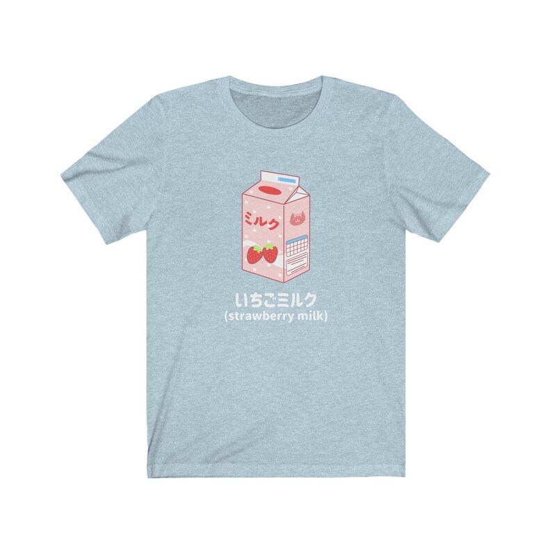 May include: A light blue t-shirt with a cartoon illustration of a carton of strawberry milk. The carton is pink and white with the Japanese word for milk, "ミルク", and the text "いちごミルク (strawberry milk)".
