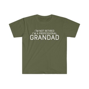 May include: A green t-shirt with white text that reads "I'm not retired I'm a professional Grandad".