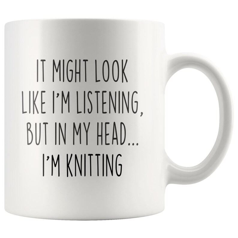 May include: White ceramic mug with black text that reads "It might look like I'm listening, but in my head... I'm knitting".