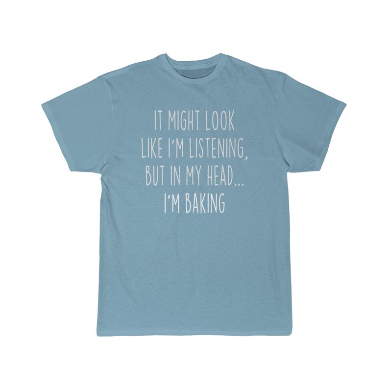 K&ouml;nnte beinhalten: Ein hellblaues T-Shirt mit dem Text "It might look like I'm listening, but in my head... I'm baking" in wei&szlig; gedruckt.