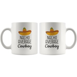 May include: Two white ceramic mugs with black text that reads "Nacho Average Cowboy" and a cartoon sombrero on each mug.
