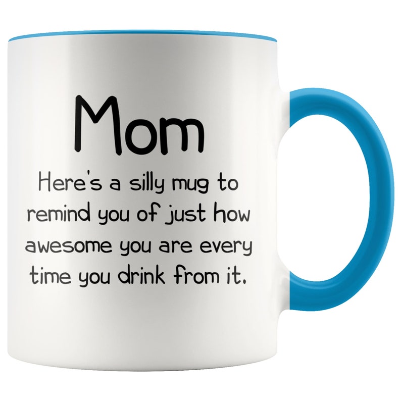 May include: White ceramic coffee mug with a blue rim and handle. The mug has black text that reads "Mom Here's a silly mug to remind you of just how awesome you are every time you drink from it."