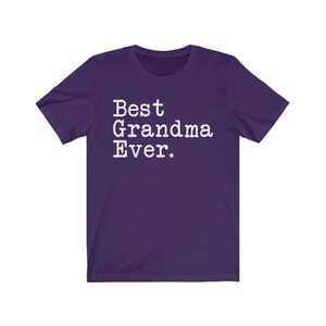 Puede incluir: Camiseta de manga corta de color morado con texto blanco que dice "Best Grandma Ever."