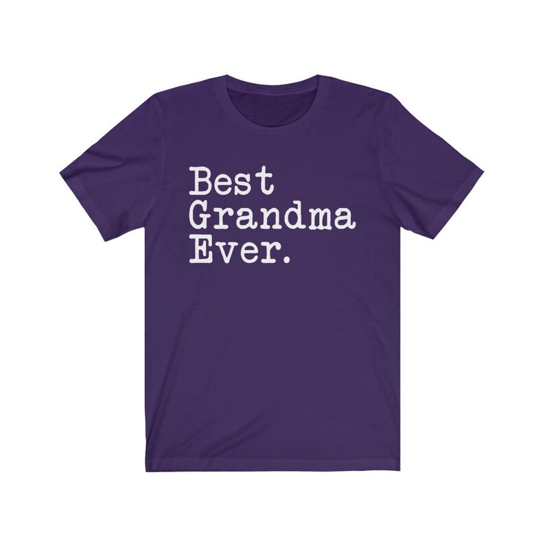 Puede incluir: Camiseta de manga corta de color morado con texto blanco que dice "Best Grandma Ever."