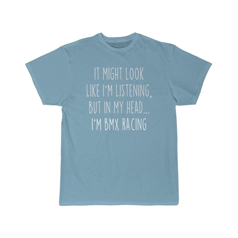 Op de afbeelding: Lichtblauw T-shirt met witte tekst die "IT MIGHT LOOK LIKE I'M LISTENING, BUT IN MY HEAD... I'M BMX RACING" luidt.