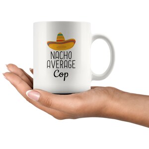 May include: White ceramic mug with a black and white graphic of a sombrero and the text "Nacho Average Cop".