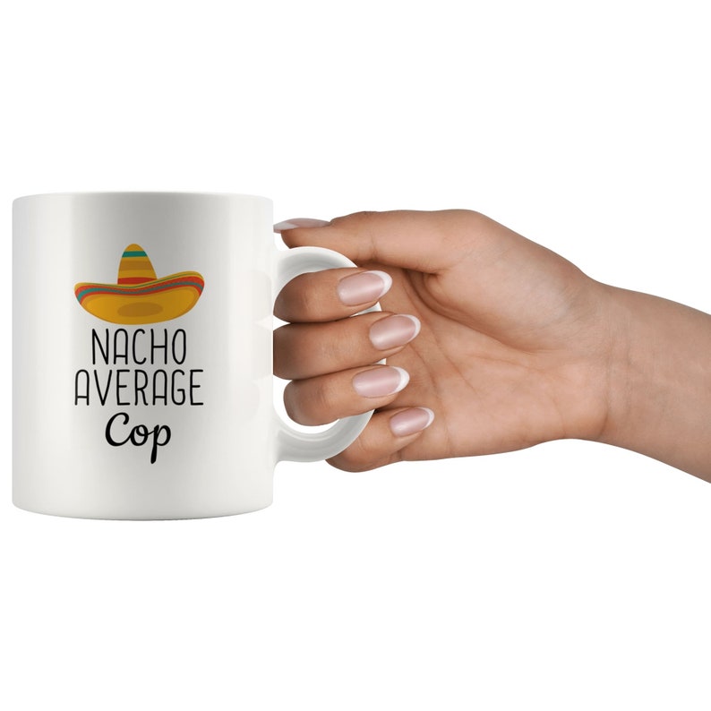 May include: White ceramic mug with a black and yellow sombrero graphic and the text "NACHO AVERAGE Cop".