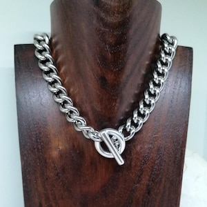 May include: A silver chain necklace with a large, chunky link design and a toggle clasp.