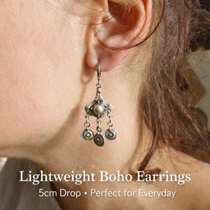 May include: Silver drop earrings with a boho design. The earrings have a central round element and three dangling charms. The text "Lightweight Boho Earrings" and "5cm Drop" is visible.