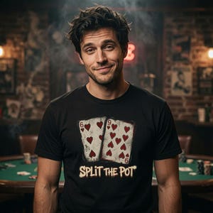 May include: A black short-sleeved t-shirt featuring a graphic of two playing cards, a six and a nine of hearts, with the text "SPLIT THE POT" printed in a distressed, off-white font underneath the cards on the front of the garment.