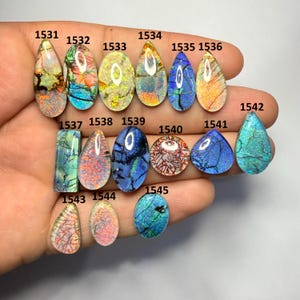 May include: A selection of polished opal gemstones in diverse shapes and colours, including teardrop, oval, and rectangular. Each stone displays unique patterns. The gemstones are labelled with numbers.