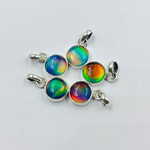 May include: Six iridescent gemstone pendants with silver settings. The gemstones are round and have a rainbow of colors, including blue, green, red, and orange.