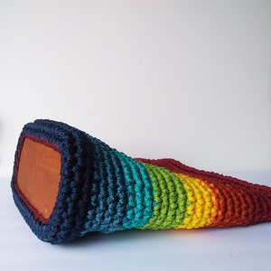 Pu&ograve; includere: Una borsa a mano in crochet arcobaleno con uno schema di colori blu scuro, verde acqua, verde, giallo, arancione e rosso. La borsa &egrave; realizzata con un filato spesso e testurizzato.