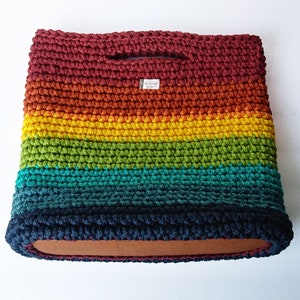 Pu&ograve; includere: Una borsa a mano in crochet arcobaleno con una base in legno. La borsa &egrave; realizzata con una variet&agrave; di colori, tra cui rosso, arancione, giallo, verde, blu e viola.