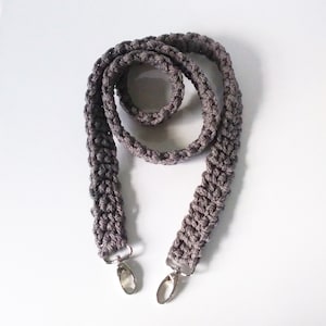 May include: A gray crocheted strap with silver clasps. The strap is about 40 inches long and is made of a thick, textured yarn.