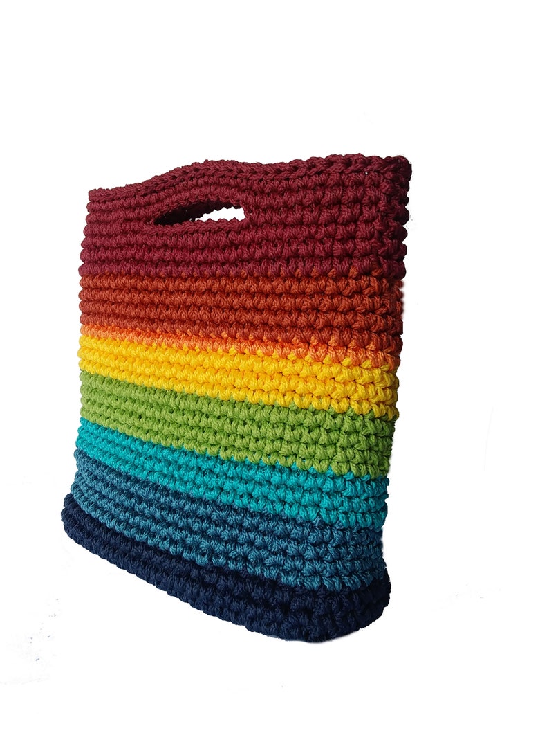 Pu&ograve; includere: Una borsa a mano in crochet dai colori dell'arcobaleno con la parte superiore bordeaux e quella inferiore blu navy. La borsa ha un'unica maniglia.