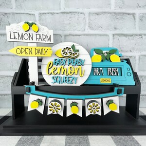 May include: A wooden lemon stand with a sign that says "Lemon Farm Open Daily". There is a round sign that says "Easy Peasy Lemon Squeezy" and a cash register that says "Farm Fresh Lemons".