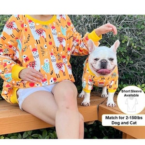 May include: Matching yellow and orange llama print sweatshirts for humans and dogs. The human sweatshirt has long sleeves and the dog sweatshirt has short sleeves. The text on the image reads "Short Sleeve Available" and "Match for 2-150lbs Dog and Cat".