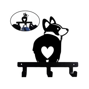 May include: Black metal key holder shaped like a corgi with a heart on its rear end. The corgi is mounted on a black metal bar with three hooks.