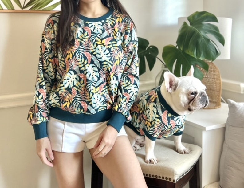 K&ouml;nnte beinhalten: Eine Frau und ein Hund tragen passende gr&uuml;ne und gelbe Hemden mit tropischem Muster. Die Frau tr&auml;gt wei&szlig;e Shorts und der Hund ist ein Franz&ouml;sischer Bulldogge.