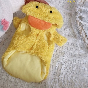 Puede incluir: Un disfraz de mascota de peluche amarillo en forma de pato con cierre de cremallera y un gran pico naranja.