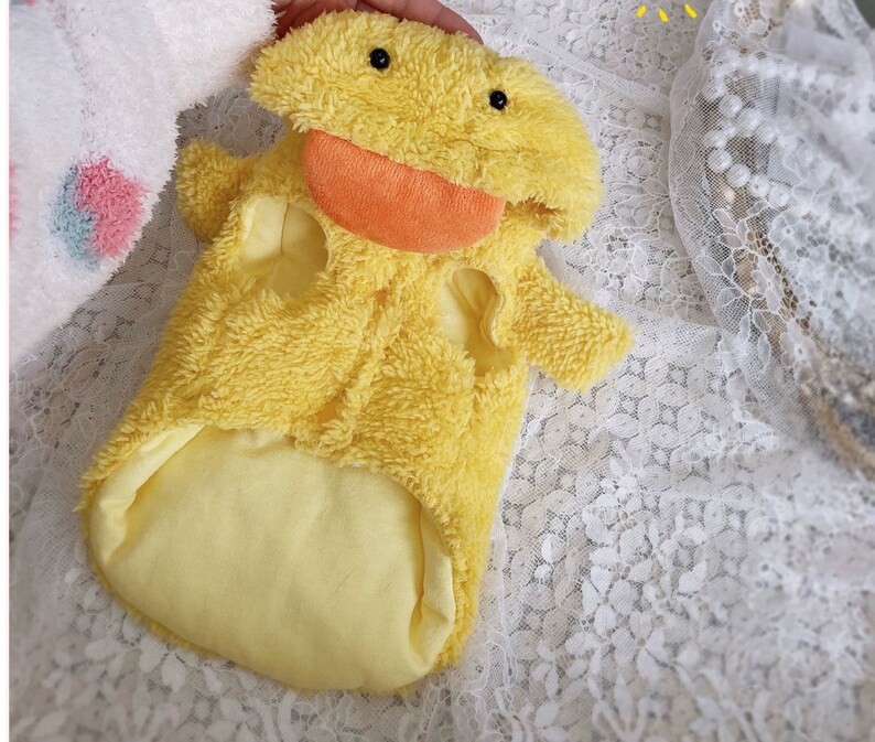 Puede incluir: Un disfraz de mascota de peluche amarillo en forma de pato con cierre de cremallera y un gran pico naranja.