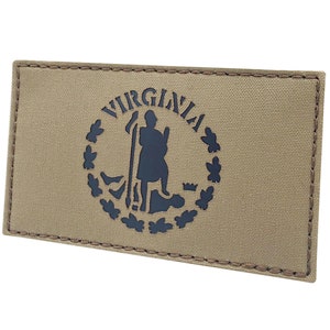 Könnte beinhalten: Ein beigefarbener Stoff-Patch mit einem schwarzen gestickten Siegel des Commonwealth of Virginia. Das Siegel zeigt einen Mann, der ein Gewehr und einen Schild hält, umgeben von einem Kranz aus Blättern. Das Wort "VIRGINIA" ist in einem Halbkreis über dem Siegel geschrieben.