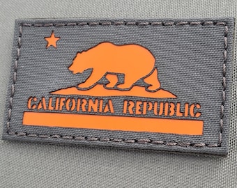 May include: A grey patch with orange stitching and a California Republic logo. The logo features a bear walking on a line with the words "California Republic" below it.