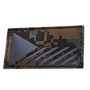 Könnte beinhalten: Ein schwarzer und grüner Tarnstoff-Patch mit einem schwarzen Dreieck und Streifen.