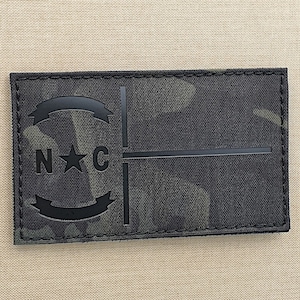 May include: Black and green camouflage patch with a black circle containing a star and the letters "N*C".