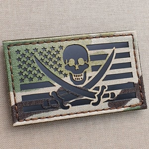May include: A black and green embroidered patch with a skull and crossbones design on a US flag background.