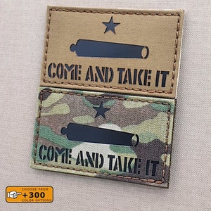 Könnte beinhalten: Zwei Versionen eines "Komm und hol es dir"-Patches. Der obere Patch ist beige mit einer schwarzen Silhouette einer Kanone und einem einzelnen Stern. Der untere Patch ist ein Tarnmuster mit einer schwarzen Silhouette einer Kanone und einem einzelnen Stern. Beide Patches haben den Text "Komm und hol es dir" in Schwarz.