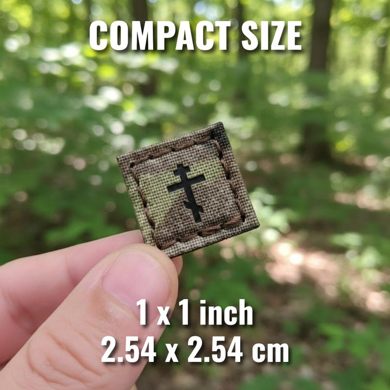 K&ouml;nnte beinhalten: Ein kleiner, quadratischer Aufn&auml;her mit Tarnmuster und einem schwarzen orthodoxen Kreuzdesign. Der Aufn&auml;her misst 2,54 x 2,54 cm. Der Text "COMPACT SIZE" steht oben.