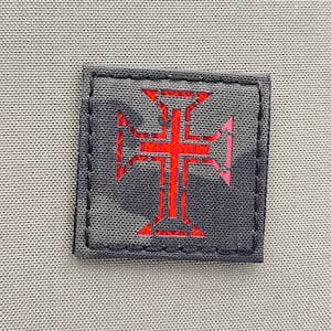 Op de afbeelding: Een zwarte patch met een rood geborduurd kruis, een symbool van Portugal.