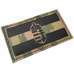 Op de afbeelding: Een zwarte en groene camouflage patch met een zwarte omtrek en een zwart granaatsymbool in het midden.