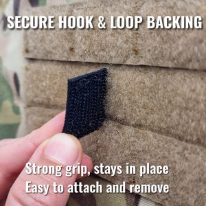 K&ouml;nnte beinhalten: Nahaufnahme eines schwarzen Klettverschlusses auf einem beigefarbenen Stoff. Der Text "SECURE HOOK & LOOP BACKING" steht oben. Der Text "Strong grip, stays in place, Easy to attach and remove" steht unten.