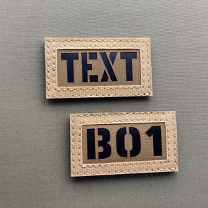 Könnte beinhalten: Zwei beigefarbene Stoffpatches mit schwarzem Text. Der obere Patch sagt "TEXT" und der untere Patch sagt "B01".