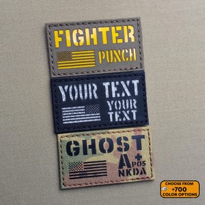 Può includere: Tre toppe rettangolari con testo e un disegno della bandiera americana. La toppa superiore recita "FIGHTER PUNCH" in giallo su sfondo grigio. La toppa centrale dice "YOUR TEXT" in bianco su sfondo nero. La toppa inferiore dice "GHOST" con testo aggiuntivo e sfondo mimetico.