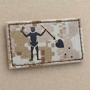 Könnte beinhalten: Ein gestickter Patch in Schwarzweiß mit einem Piratensymbol. Das Symbol ist eine Strichmännchenfigur, die einen Speer hält und auf ein Herz zeigt. Der Patch befindet sich auf einem braunen Tarnmusterhintergrund.