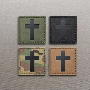 Könnte beinhalten: Vier quadratische Aufnäher mit einem mittigen schwarzen Kreuz. Die Aufnäher sind in Olivgrün, Schwarz, Tarnmuster und Hellbraun erhältlich. Jeder Aufnäher hat einen genähten Rand und eine robuste Stoffkonstruktion mit matter Oberfläche.